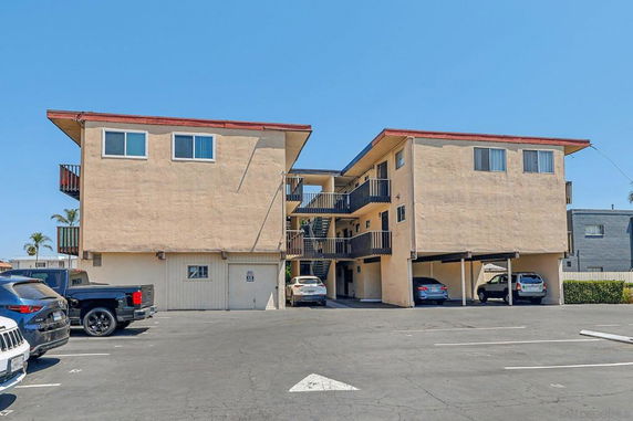 Front view of a multi-story apartment building with parking area underneath.