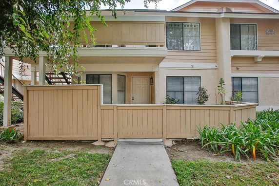 Front view of a two-story residential building with a fenced patio.