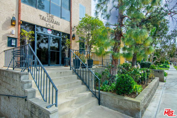 Front view of a building entrance with stairs and surrounding landscaping.