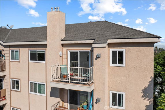 Front view of a multi-story building with balconies and chimney.