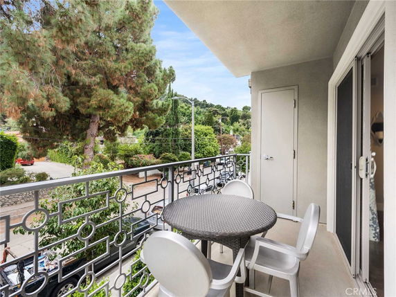 Balcony view with outdoor furniture overlooking trees and street.