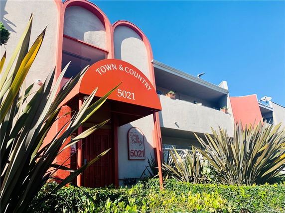 Front view of a multi-story building with red accents and balconies.