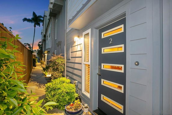 Front view of a modern house with a sleek door and exterior lighting.