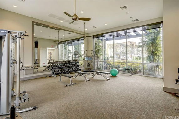 Interior view of a gym with various exercise equipment and large windows.