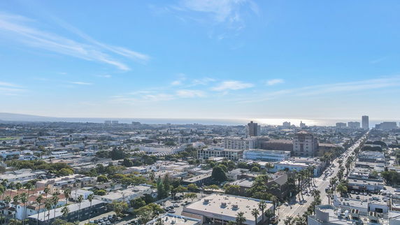 Panoramic view of a cityscape with numerous buildings and a distant view of the ocean.