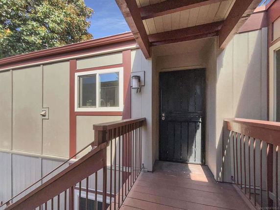 Front view of an exterior door with wooden railing and siding.