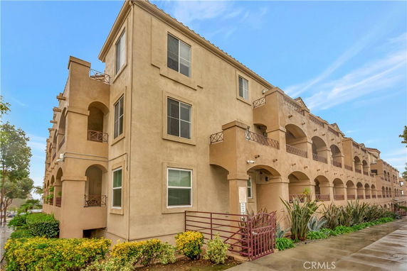 Front view of a multi-story apartment building with balconies and arches.