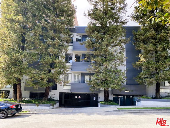 Front view of a multi-story residential building with a gated entrance.
