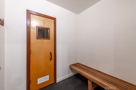 Interior of a room with a wooden bench and door, possibly a sauna or steam room.