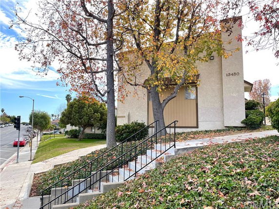 Front view of a two-story building with beige exterior and trees around it.