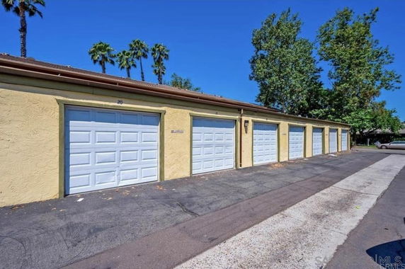 Row of covered parking garages with white doors.