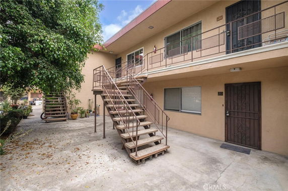 Front view of a two-story apartment building with exterior staircases and multiple entry doors.