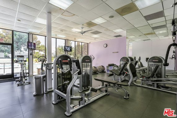 Interior of a gym area with exercise machines and large windows.