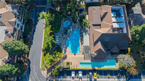 Aerial view of a building with a large swimming pool and surrounding greenery.