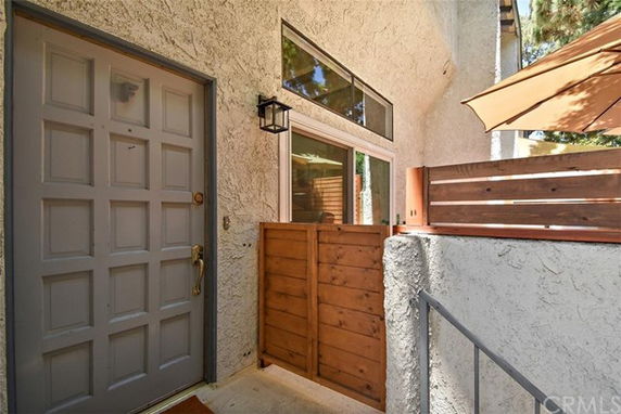 Front view of a building entrance with a gray door and wooden privacy panel.