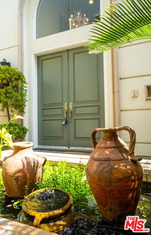 Front view of a building entrance with double doors and decorative vases.