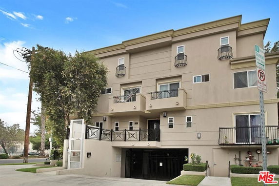 Front view of a multi-story building with balconies and a covered parking area.
