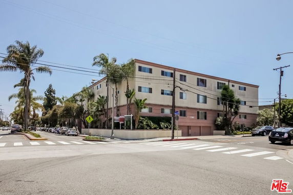 Front view of a multi-story apartment building on a street corner.