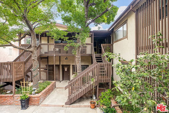 Front view of a two-story residential building with a wooden staircase and balcony.