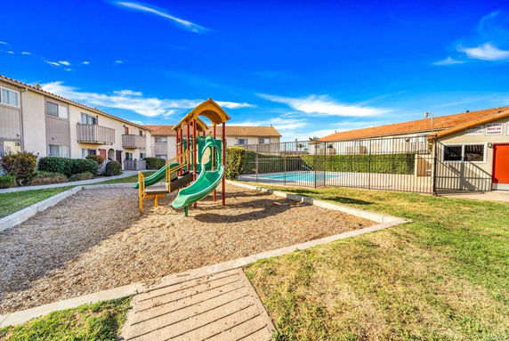 Outdoor play area with a playground featuring slides and other play equipment.