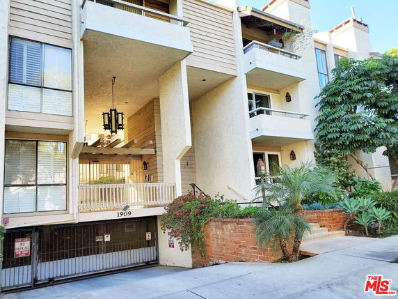 Front view of a multi-story building with balconies and a gated entrance.
