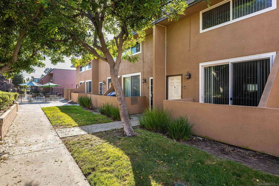 Front view of a multi-story residential building with a pathway and a fence.