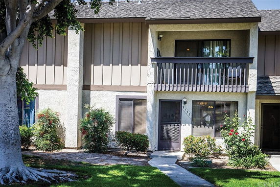 Front view of a two-story house with a balcony and entrance door.