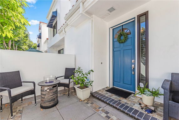 View of the front entrance of a house with a blue door and small patio.