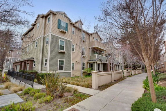 Front view of a multi-story residential building with a walkway and garden area.