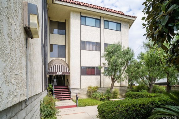 Front view of a multi-story building with an entrance canopy and surrounding greenery.