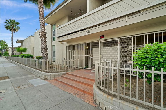 Front view of a multi-story building with a gated entrance and palm trees.