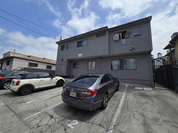 Outdoor parking area in front of a two-story building.