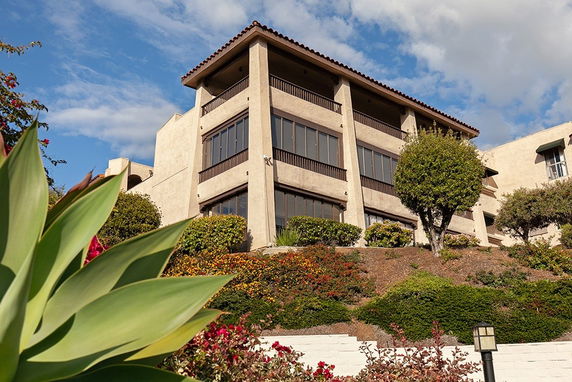 Front view of a multi-story building with a tiled roof and large windows.
