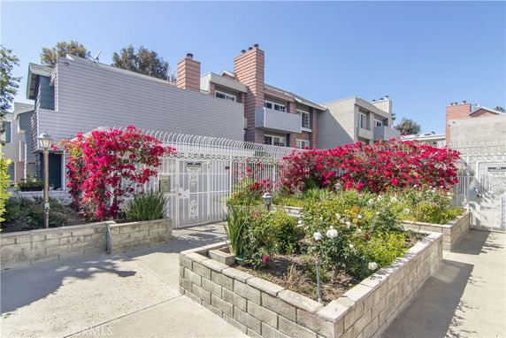 Front view of a multi-story residential building with a gated entrance and garden.