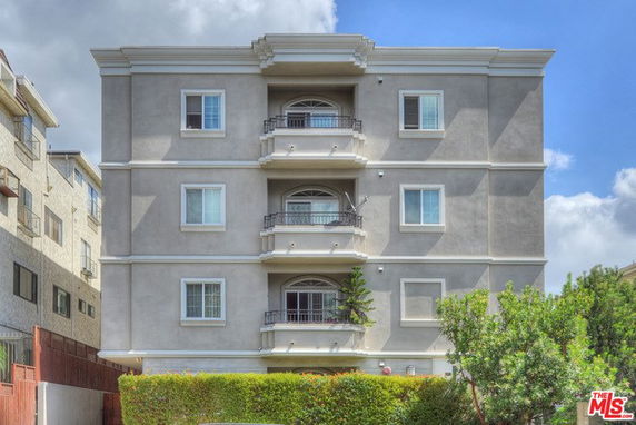 Front view of a four-story apartment building with multiple balconies.