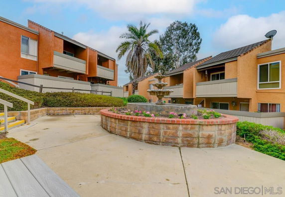 Front view of apartment buildings with balconies and a central fountain in the courtyard.