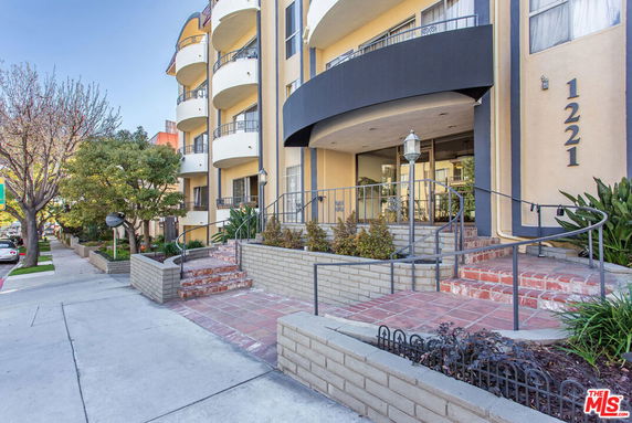 Front view of a multi-story residential building with balconies and entrance steps.