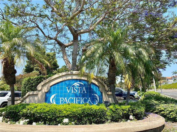 Decorative entrance sign with blue tiles and palm trees around.