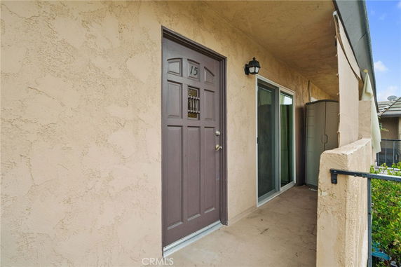 Front view of a house entrance with a brown door and adjacent sliding glass door.