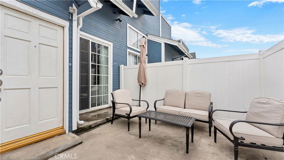 Front view of a house with blue siding and a small patio area with outdoor seating.