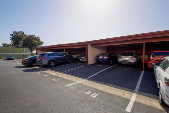 Covered parking area with multiple cars parked in designated spaces.
