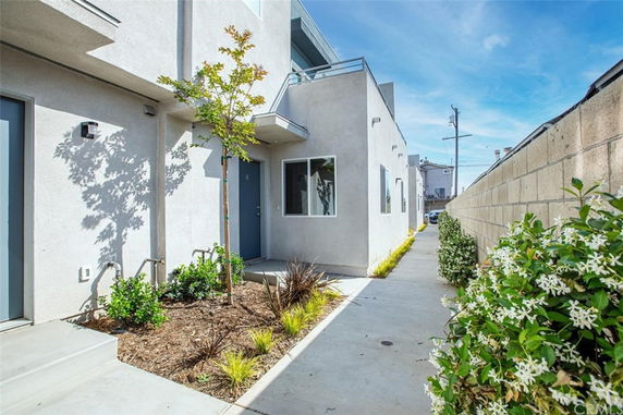 Front view of a modern multi-story building entrance with a narrow pathway.