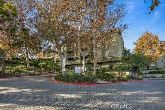Front view of a building surrounded by trees with a paved driveway.