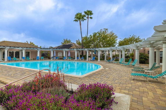 Outdoor swimming pool area with seating and a pergola structure.