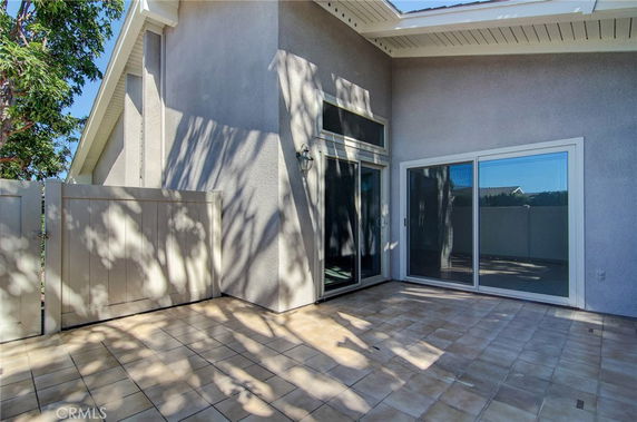 Exterior view of a house with sliding glass doors and a tiled patio area.