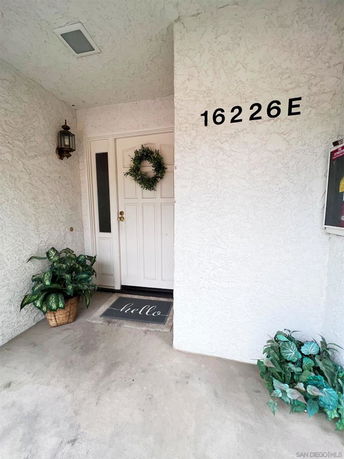 Front view of a house entrance with plants and a welcome mat.