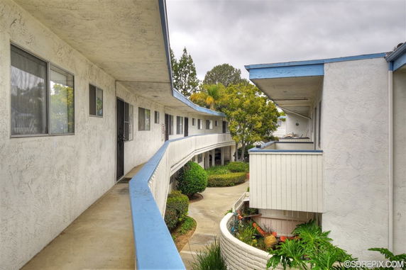 View of a multi-story building with a balcony and walkway.