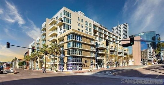 Front view of a multi-story building on a street corner with balconies and large windows.