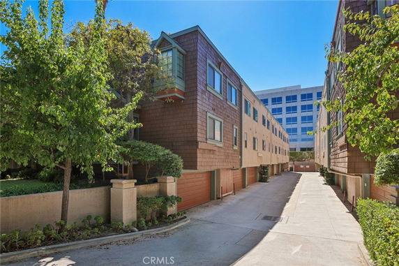 View of a multi-story apartment building with trees and a driveway.
