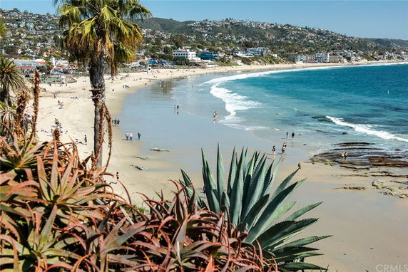 Panoramic view of a beach with people walking and playing along the shoreline.